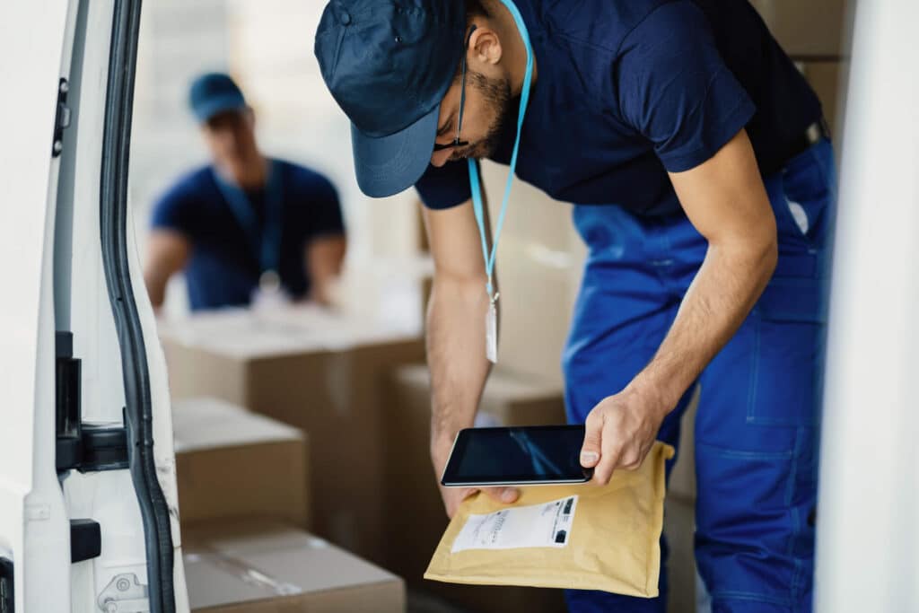 A certified medical courier uses a phone to scan a parcel that is out for delivery.