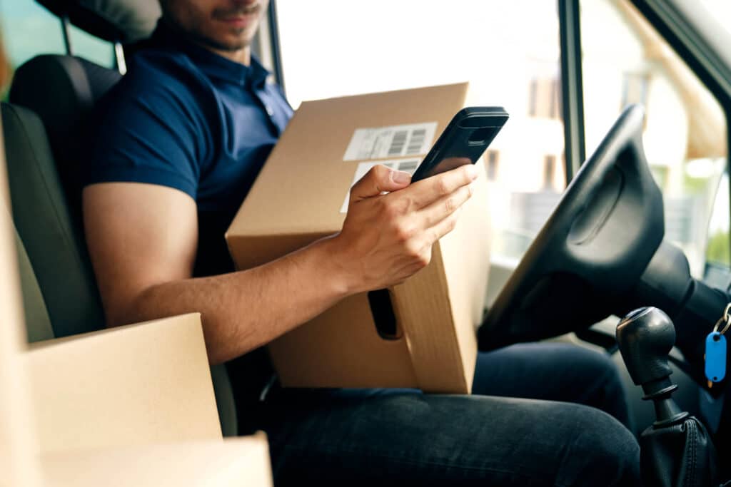Close up of a medical courier checking a package using portable information device.