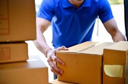 man in blue shirt picking up box
