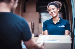 smiling woman handing off box