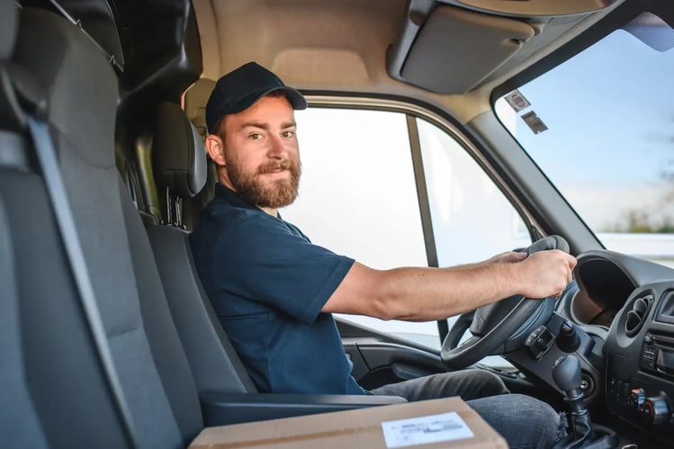 delivery man in truck with package looking at camera